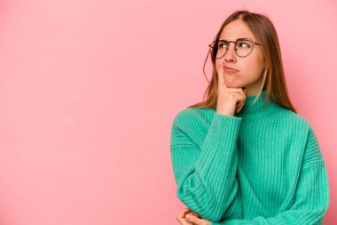 Pembe arka planda soyutlanmış beyaz bir kadın şüpheli ve şüpheci bir ifadeyle yana bakıyor..