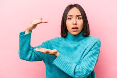 Pembe arka planda izole edilmiş genç İspanyol kadın elleri arasında bir kopya alanı tutarken şok ve hayrete düştü..