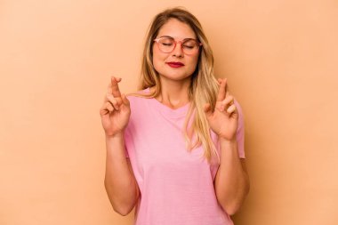 Beyazlı genç bir kadın bej arka planda izole edilmiş şans dilemek için şans diliyor.