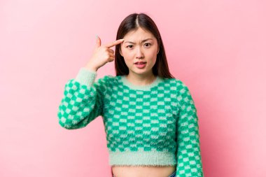 Pembe arka planda izole edilmiş genç Çinli kadın işaret parmağıyla bir hayal kırıklığı gösteriyor..