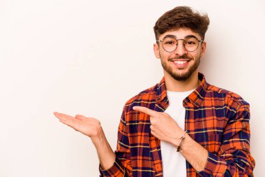 Beyaz arka planda izole edilmiş genç İspanyol bir adam heyecanlı bir şekilde avuç içinin bir kopyasını tutuyor..