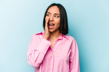 Genç İspanyol kadın mavi arka planda izole edilmiş, heyecanlı bir şekilde bağırıyor..