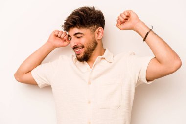 Beyaz arka planda izole edilmiş genç bir İspanyol özel bir günü kutluyor, atlıyor ve enerjiyle kollarını kaldırıyor..