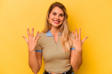 Sarı arka planda izole edilmiş genç beyaz kadın on numarayı elleriyle gösteriyor..