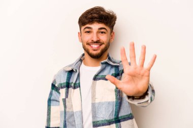 Beyaz arka planda izole edilmiş genç İspanyol adam gülümseyerek beş numarayı parmaklarıyla gösteriyor..