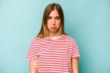 Genç beyaz kadın mavi arka planda izole edilmiş üzgün, ciddi yüzlü, mutsuz ve hoşnutsuz..
