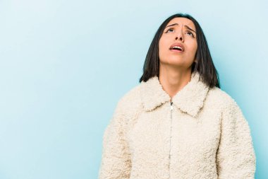 Mavi arka planda izole edilmiş genç İspanyol kadın çok kızgın, öfkeli, hayal kırıklığına uğramış.