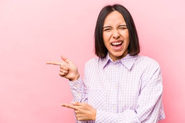 Pembe arka planda izole edilmiş genç İspanyol kadın işaret parmaklarıyla fotokopi alanını işaret ederek heyecan ve arzusunu ifade ediyor..