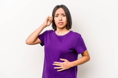Latin kökenli hamile bir kadın, beyaz arka planda izole edilmiş kulakları elleriyle kapatıyor..