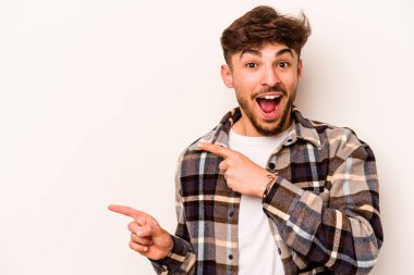 Beyaz arka planda izole edilmiş genç İspanyol adam işaret parmaklarıyla fotokopi alanını işaret ederek heyecan ve arzuyu ifade ediyor..