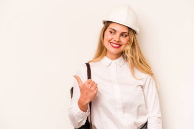 Miğferli ve elinde planları olan genç bir mimar. Beyaz arka plan noktalarına izole edilmiş. Baş parmak uzakta, gülen ve kaygısız..