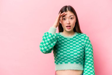 Pembe arka planda izole edilmiş genç Çinli kadın yüksek sesle bağırıyor, gözleri açık ve elleri gergin tutuyor..