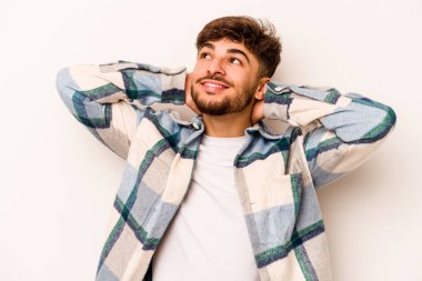 Beyaz arka planda izole edilmiş genç İspanyol bir adam kendini güvende hissediyor, elleri başının arkasında..