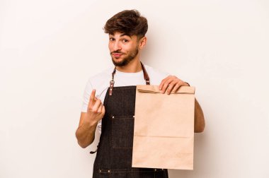 Genç İspanyol tezgahtar, beyaz arka planda izole edilmiş bir çanta tutuyor. Sanki seni davet ediyormuş gibi işaret ediyor..