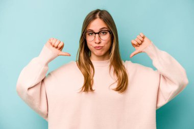 Mavi arka planda izole genç beyaz kadın gururlu ve kendinden emin hissediyor, örnek olarak..