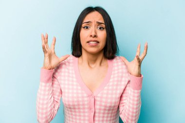 Mavi arka planda izole edilmiş genç İspanyol kadın gökyüzüne haykırıyor, yukarı bakıyor, hayal kırıklığına uğramış..