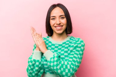 Pembe arka planda izole edilmiş genç İspanyol kadın enerjik ve rahat hissediyor, ellerini ovuşturuyor..