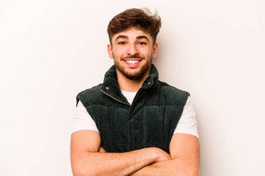 Beyaz arka planda kendini güvende hisseden, kararlılıkla kollarını kavuşturan genç İspanyol bir adam..