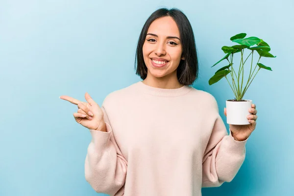 Mujer Hispana Joven Sosteniendo Una Planta Aislada Sobre Fondo Azul —  Fotos de Stock