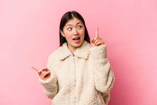 Joven Mujer China Aislada Sobre Fondo Rosa Señalando Diferentes Espacios —  Fotos de Stock