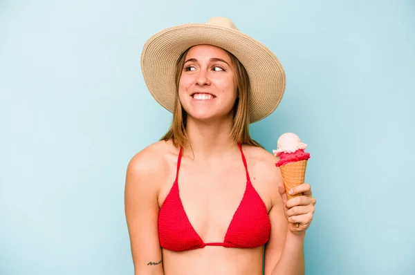 Jovem Caucasiana Vestindo Biquíni Segurando Sorvete Isolado Fundo Azul Sonhando — Fotografia de Stock