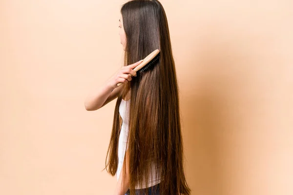 Jovem Mulher Asiática Pentear Seu Cabelo Isolado Fundo Bege — Fotografia de Stock