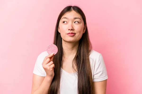 年轻的亚洲女人手握粉红背景的面部海绵 梦想着实现自己的目标和目的 — 图库照片