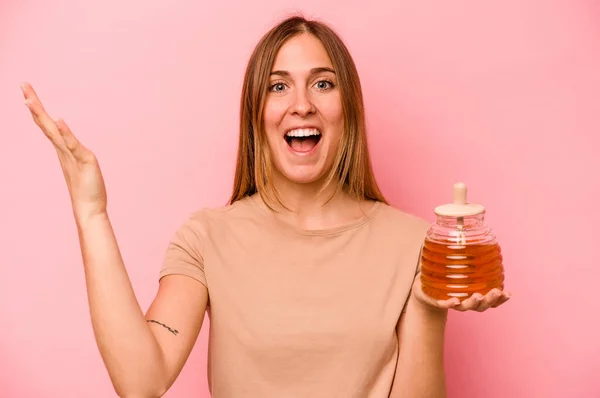 Young Caucasian Woman Holding Honey Isolated Pink Background Receiving Pleasant — Stock Photo, Image