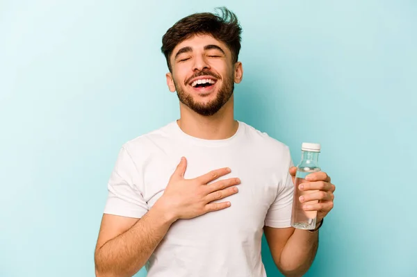 Pemuda Hispanik Memegang Botol Air Terisolasi Latar Belakang Putih Tertawa — Stok Foto