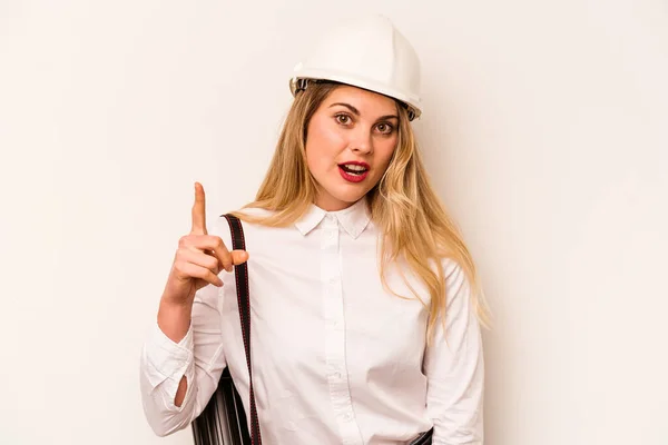 Young architect woman with helmet and holding blueprints isolated on white background having an idea, inspiration concept.