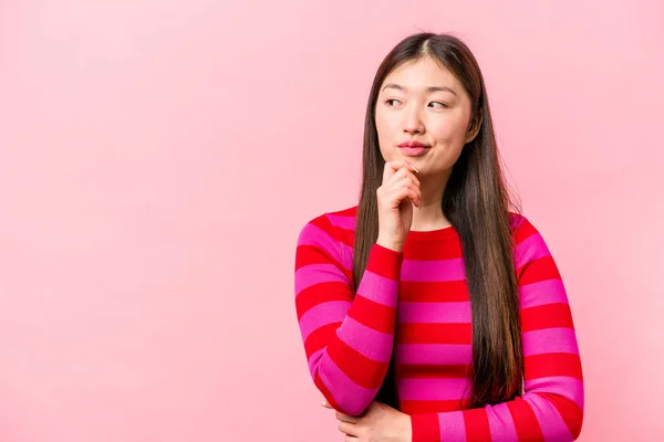 一个被粉色背景隔离的年轻中国女人 在想什么东西时 放松了对复制空间的思考 — 图库照片