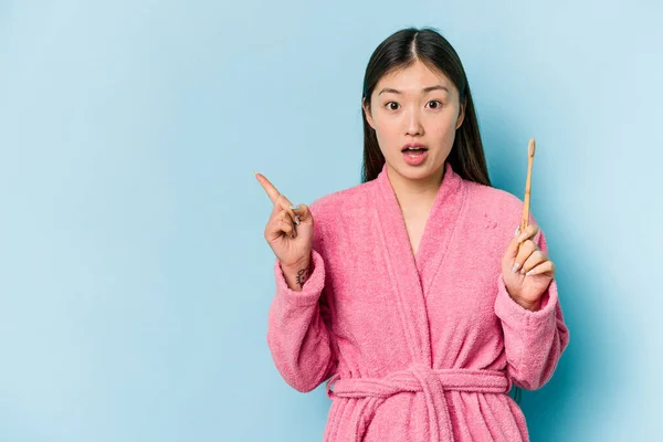 年轻的亚洲女人穿着浴衣刷牙 用粉红衬托着侧边 — 图库照片