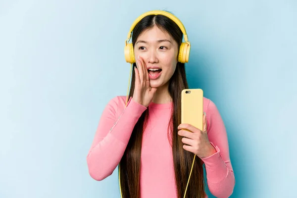 Jovem Mulher Asiática Ouvindo Música Isolada Fundo Azul Gritando Segurando — Fotografia de Stock