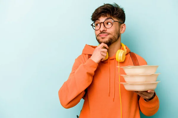 Joven Estudiante Hispano Sosteniendo Tupperware Aislado Sobre Fondo Azul Mirando — Foto de Stock