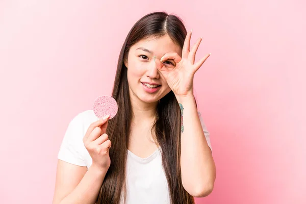 年轻的亚洲女人 手握粉红背景的面部海绵 兴奋极了 眼睛上保持着好的姿势 — 图库照片