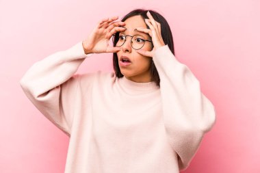 Pembe arka planda izole edilmiş genç İspanyol kadın bir başarı fırsatı bulmak için gözlerini açık tutuyor..