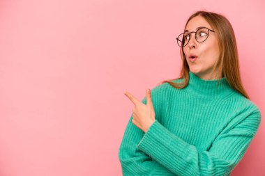 Pembe arka plan noktalarında izole edilmiş genç beyaz kadın başparmak uzakta, gülüyor ve kaygısız..