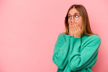 Pembe arka planda izole edilmiş beyaz bir kadın. Düşünceli bir şekilde ağzıyla ağzını kapatan bir fotokopi odasına bakıyor..