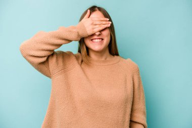 Mavi arka planda soyutlanmış beyaz bir kadın elleriyle gözlerini kapatıyor, gülümseyerek bir sürpriz bekliyor..