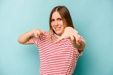 Mavi arka planda izole edilmiş genç beyaz kadın pençelerini kedi taklidi yaparken gösteriyor, agresif bir hareket..