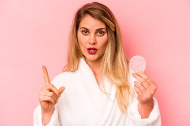 Pembe arka planda yüzü süngerle kaplanmış beyaz bir kadının harika bir fikri var, yaratıcılık kavramı..