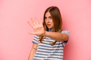 Pembe arka planda izole edilmiş genç beyaz kadın yakın bir tehlike nedeniyle şoka uğruyor.