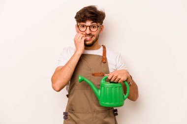 Genç bahçıvan elinde su dolu bir teneke tutuyordu. Beyaz arka planda izole edilmiş tırnak yiyordu. Gergin ve tedirgindi..