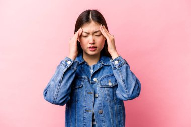 Genç Çinli kadın pembe arka planda izole edilmiş tapınaklara dokunuyor ve baş ağrısı çekiyor..