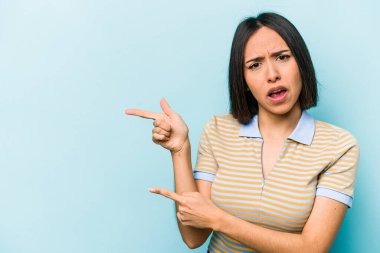 Mavi arka planda izole edilmiş genç İspanyol kadın işaret parmaklarıyla fotokopi alanını işaret ederek heyecan ve arzusunu ifade ediyor..