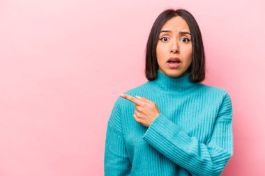 Pembe arka planda izole edilmiş genç İspanyol kadın yan tarafı gösteriyor.