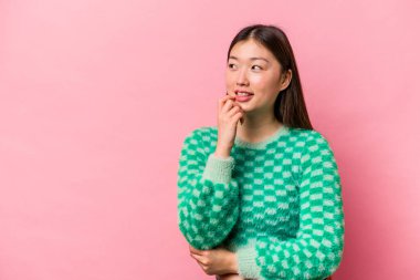 Pembe arka planda izole edilmiş genç Çinli kadın rahatlamış fotokopi odasına bakan bir şey düşünüyor..