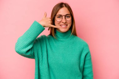 Pembe arka planda izole edilmiş genç beyaz kadın parmaklarıyla bir cep telefonu hareketi gösteriyor..