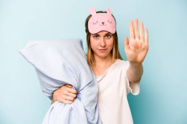 Mavi arka planda izole edilmiş pijama giyen beyaz bir kadın elini uzatıp dur işareti göstererek seni engelliyor..