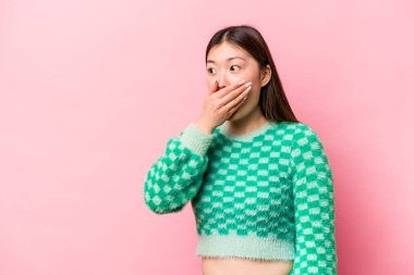 Genç Çinli bir kadın pembe arka planda izole edilmiş, düşünceli bir şekilde ağzını kapayan bir fotokopi odasına bakıyor..